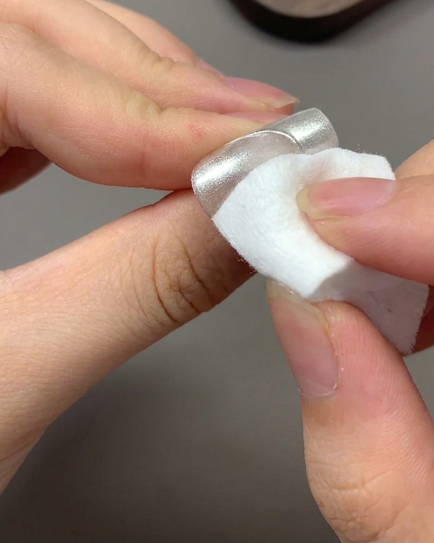 A clean dry wipe removing excess floating chrome powder from a nail.