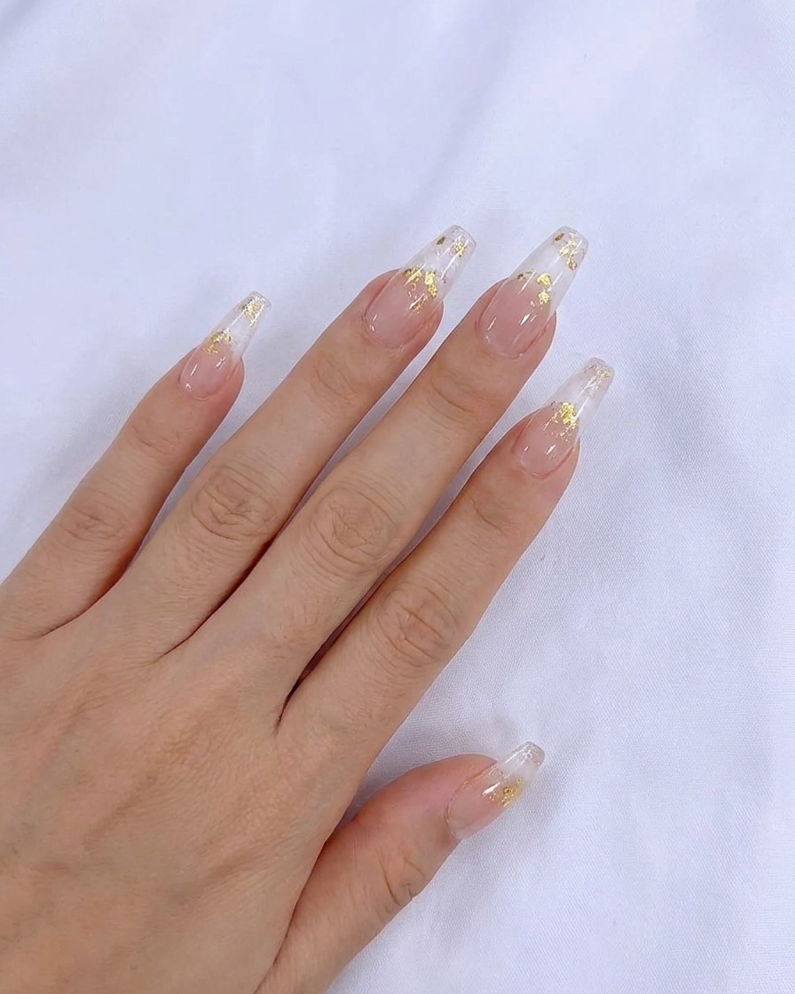 A brush applying a smooth coat of sheer nude gel polish onto the natural nail.