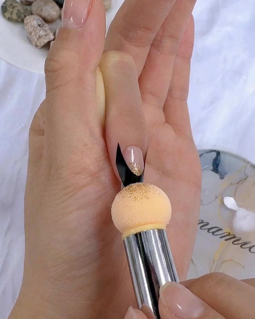 A sponge tool dabbing color gel onto a nail near a French sticker.