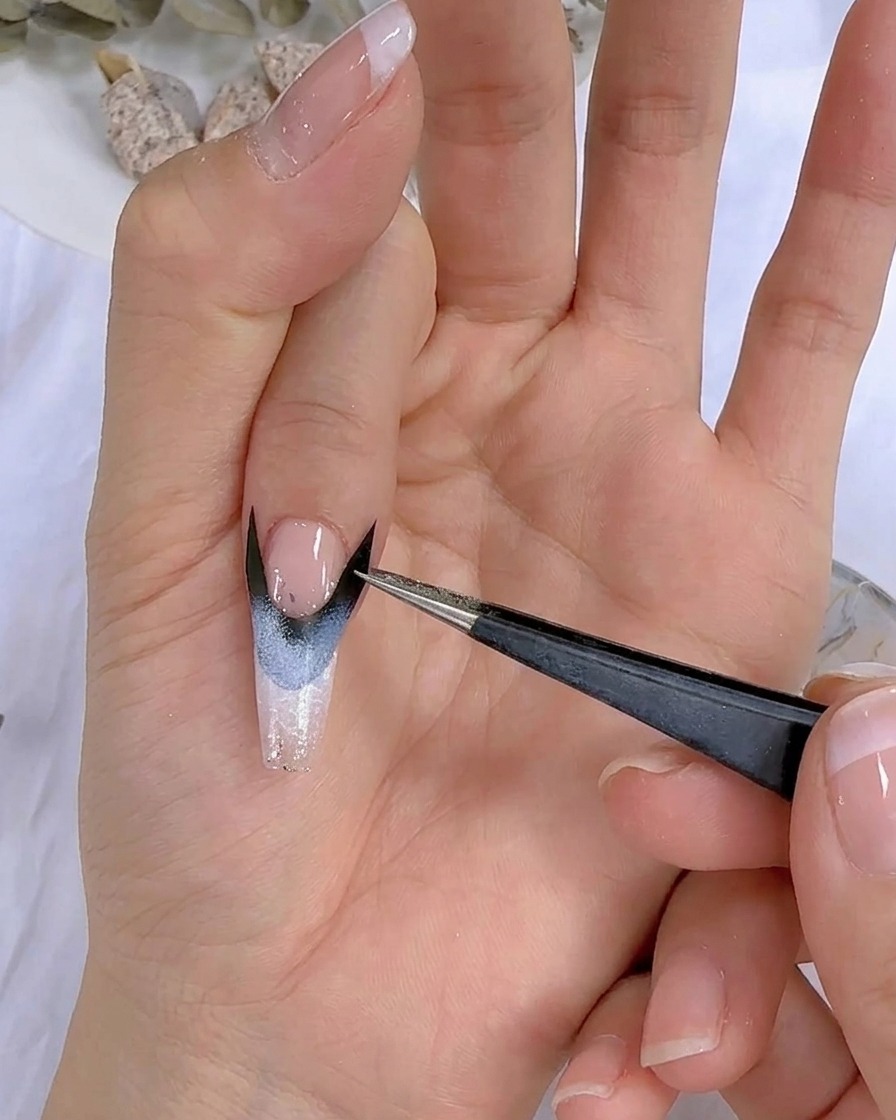 A close-up of a hand with nail art placed under a UV LED lamp.