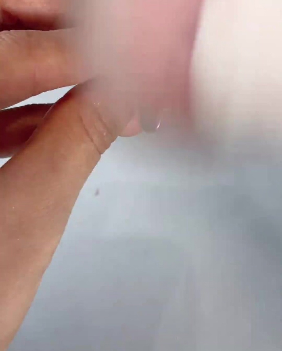 A soft fluffy brush sweeping away residual powder dust from a manicured finger.