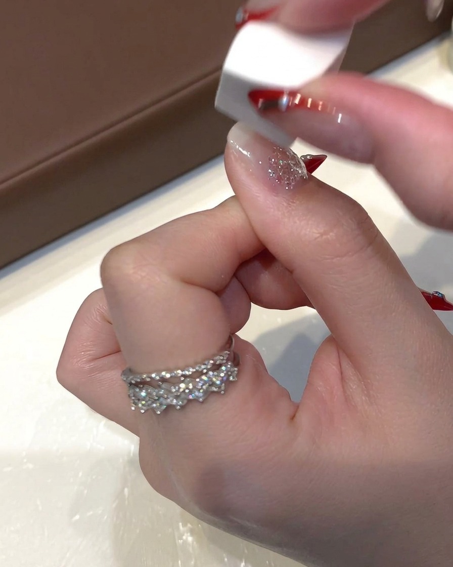 A small white makeup sponge tapping lightly over wet sequin gel on the nail to flatten the glitter.