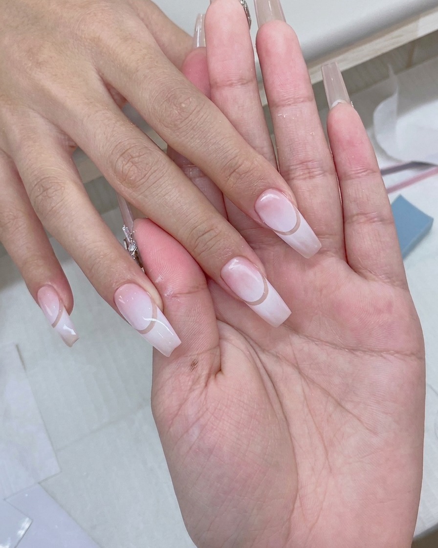 A gel brush applying a clear, glossy top coat over a finished gradient nail design.