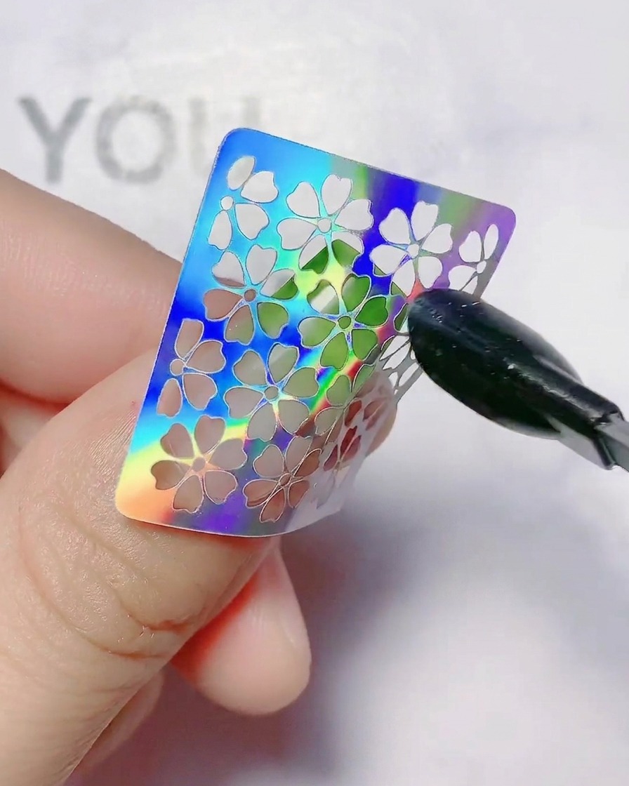 A hollow flower nail sticker being pressed onto a gradient nail.