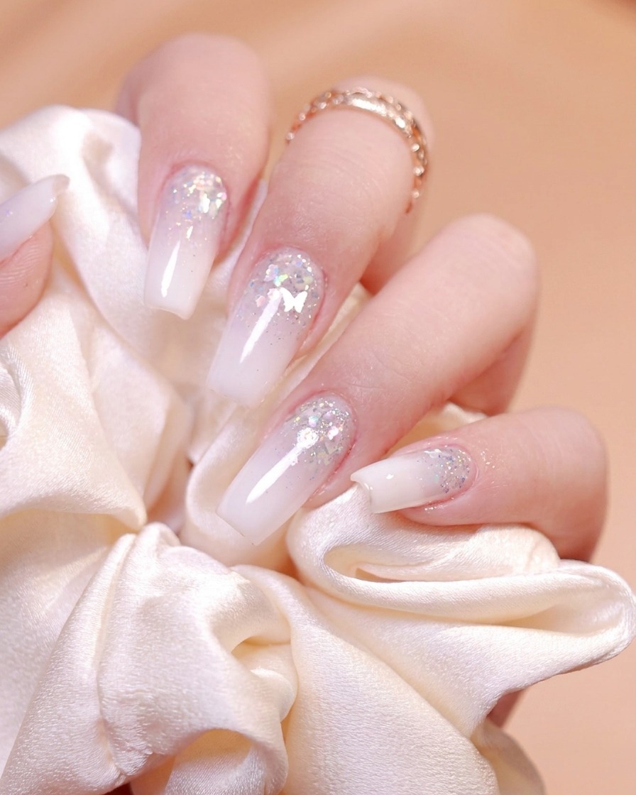 A fine nail brush picking up silver glitter gel from a small black container.