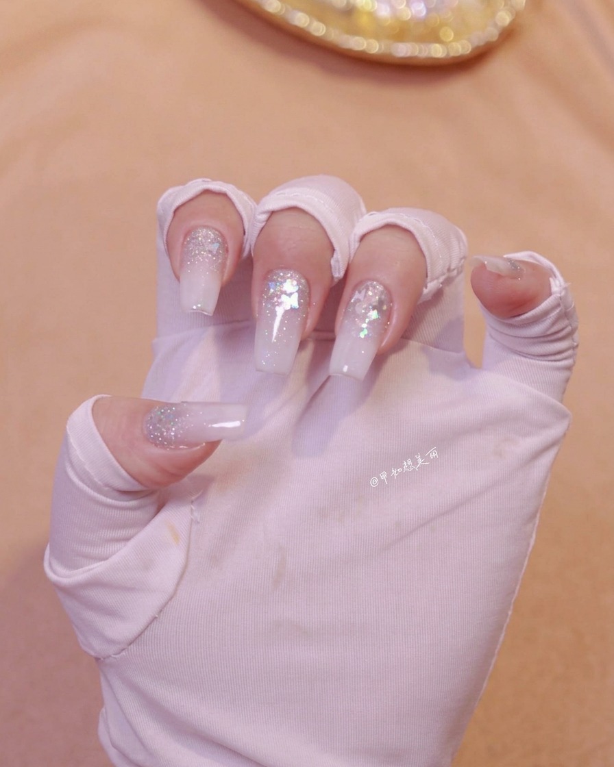 A hand positioned under a nail lamp to cure the freshly applied nail art layer.