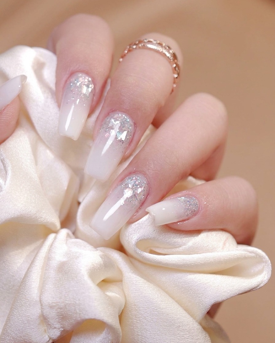 A brush applying a glossy top coat evenly onto the surface of a decorated nail.