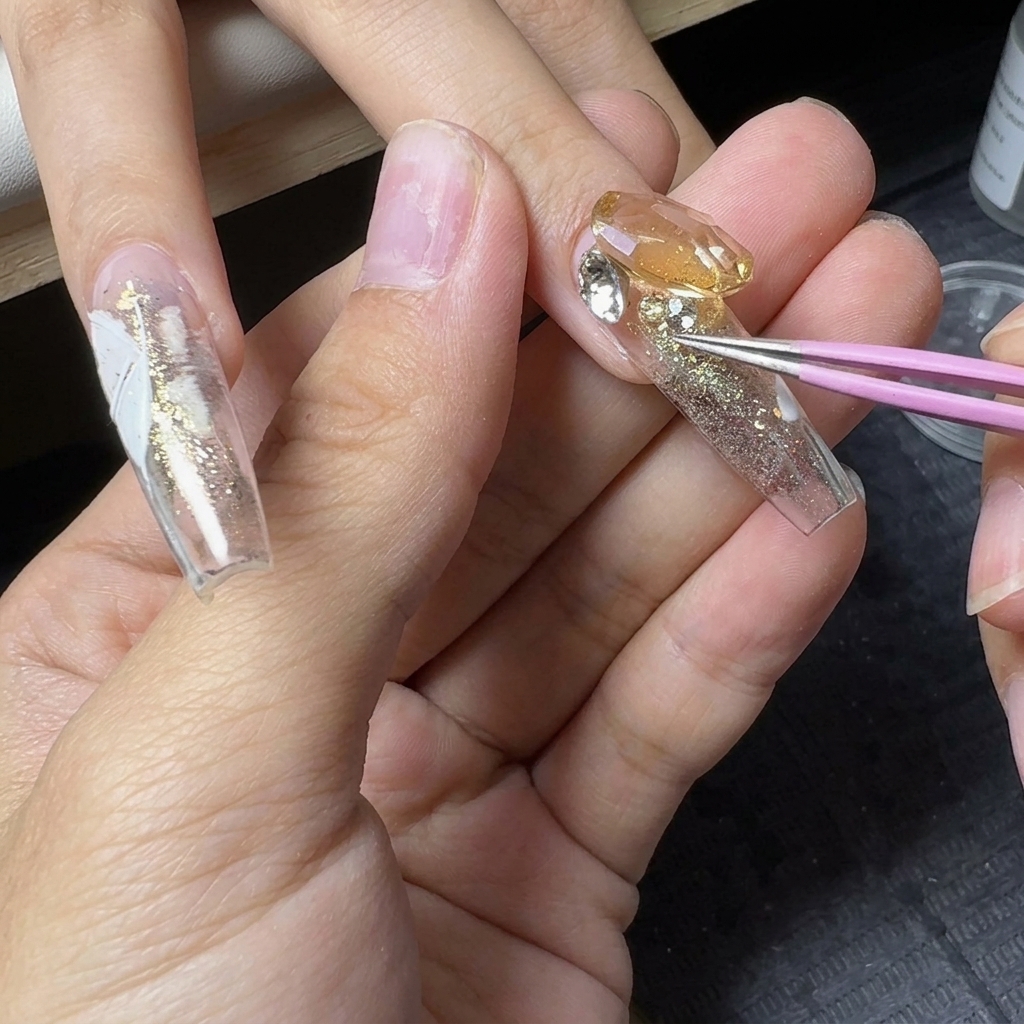 Precision tweezers placing small crystal rhinestones around a large central gemstone on a glitter nail.