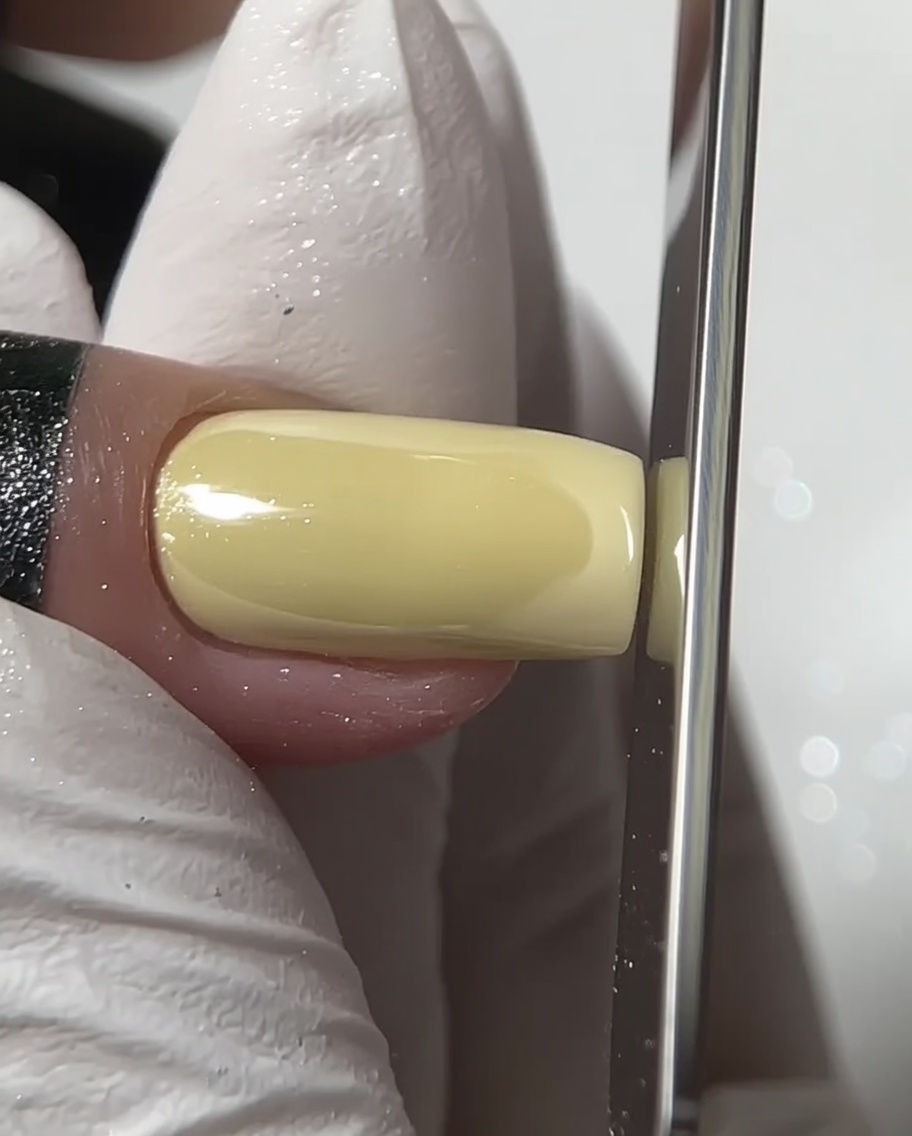 A nail file shaping the free edge of a square chrome nail.