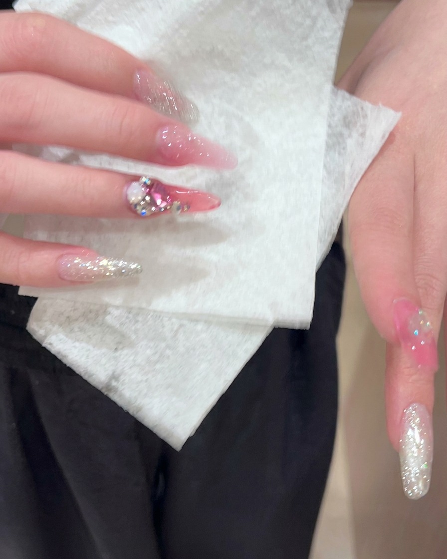 A paper wipe delicately cleaning the surface of prepped and decorated acrylic nails.