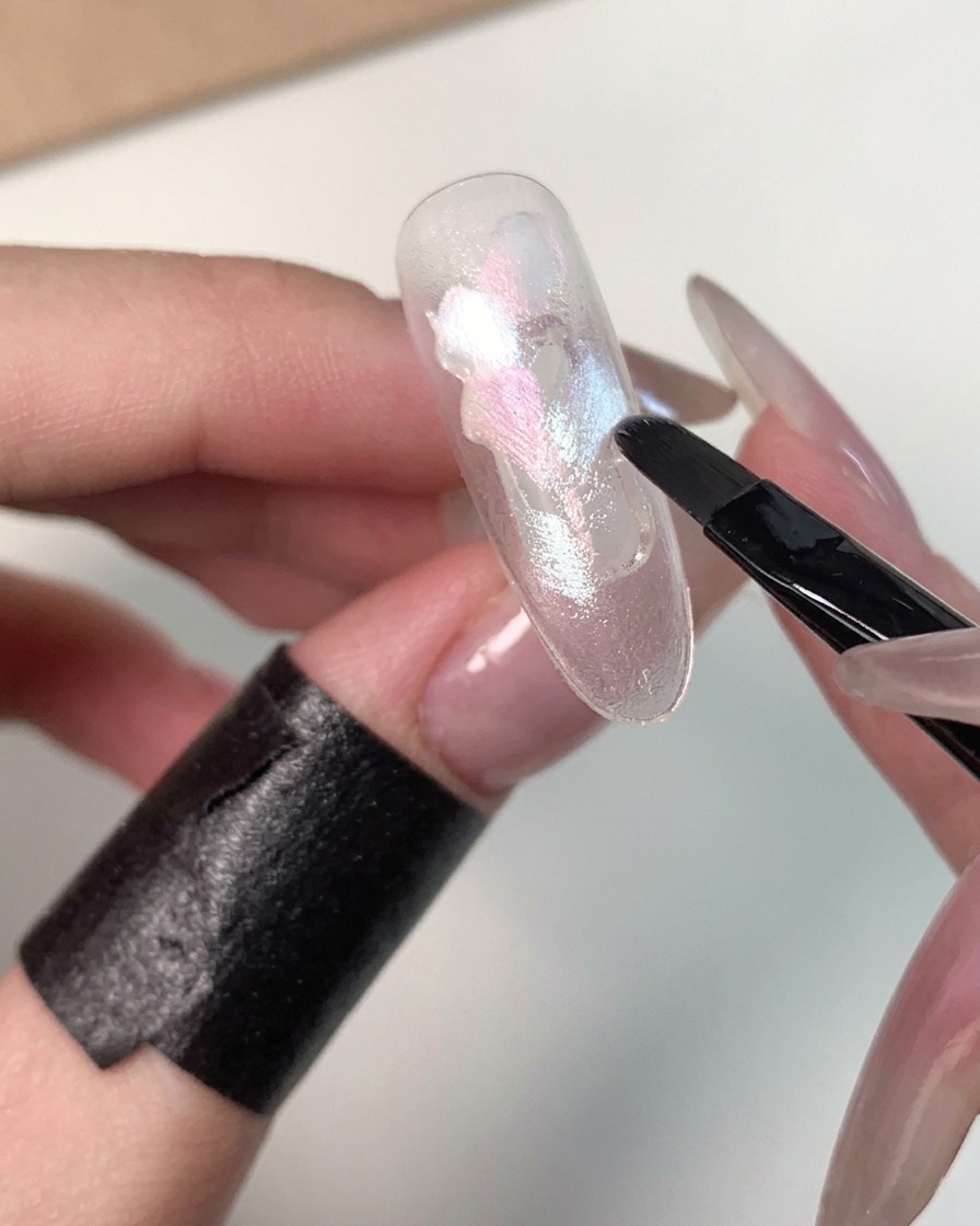 A close-up view of blue gel being applied around the outer edges of the nail.