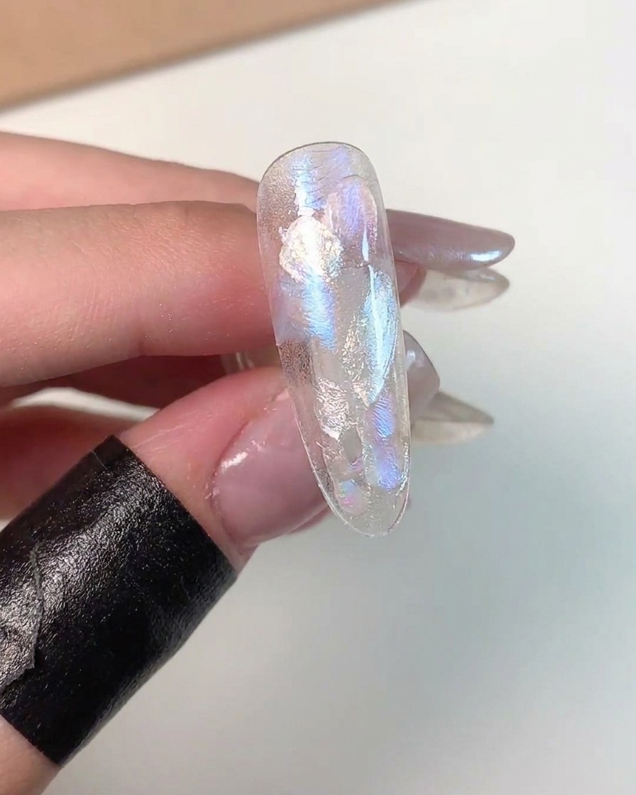 A close-up showing cat eye gel being magnetized in the lower corner of a practice nail tip.