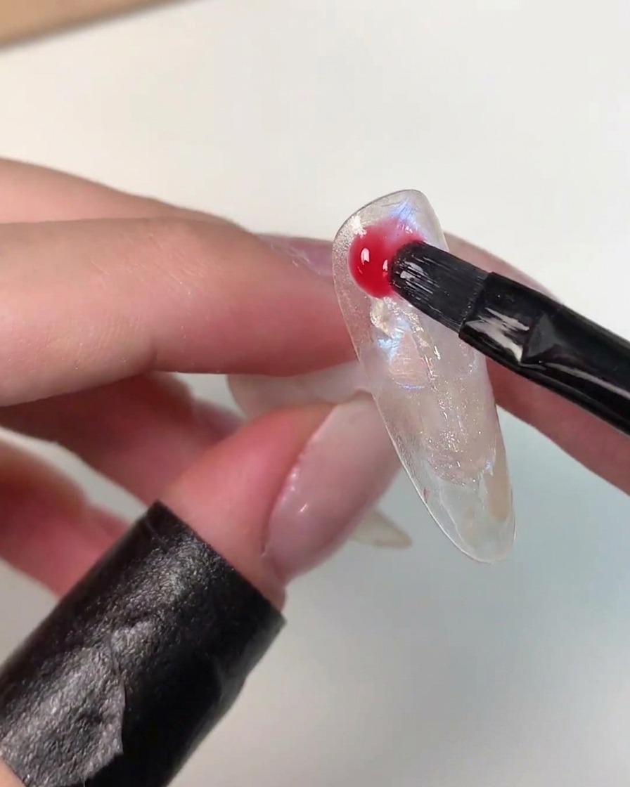 A brush applying vibrant Eiko Esaka color gel randomly across the nail art surface.