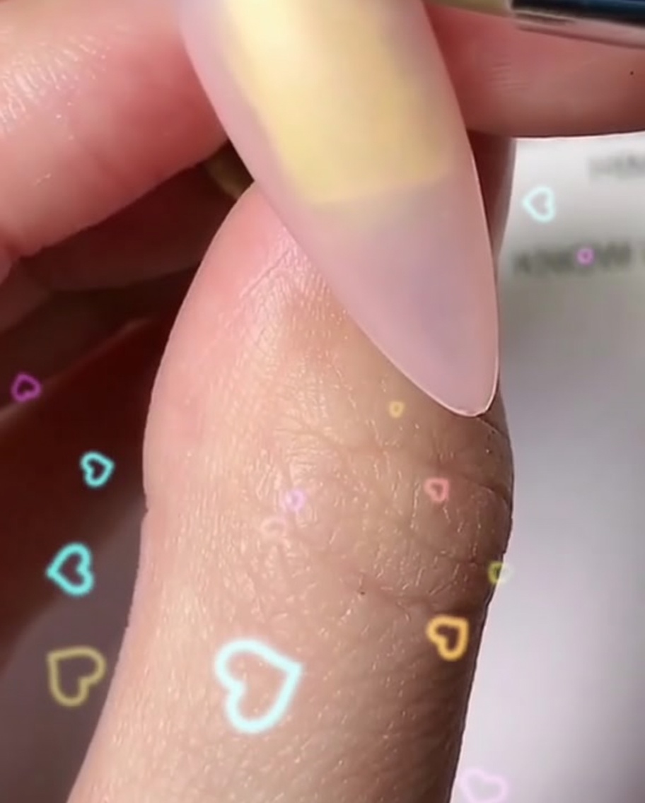 A fine brush painting individual rounded white petals to form a blossom shape on a fingernail.