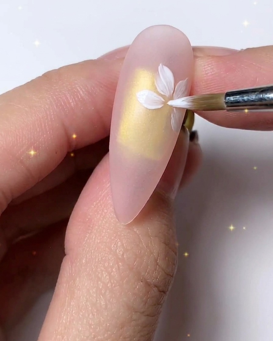 A fine brush refining and layering white petals for a delicate look on the nail.