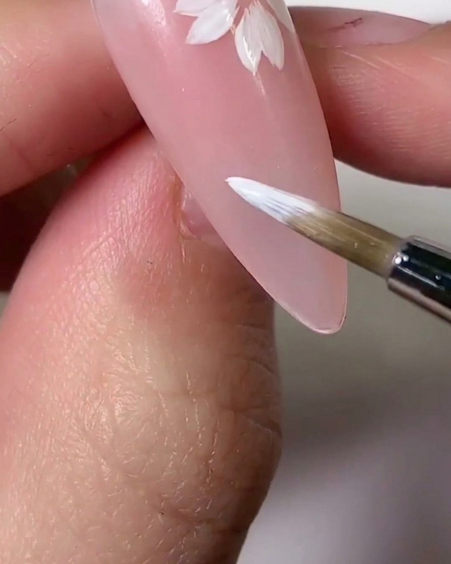 A brush applying light pink gel tint over sections of the white petals for a gradient effect.