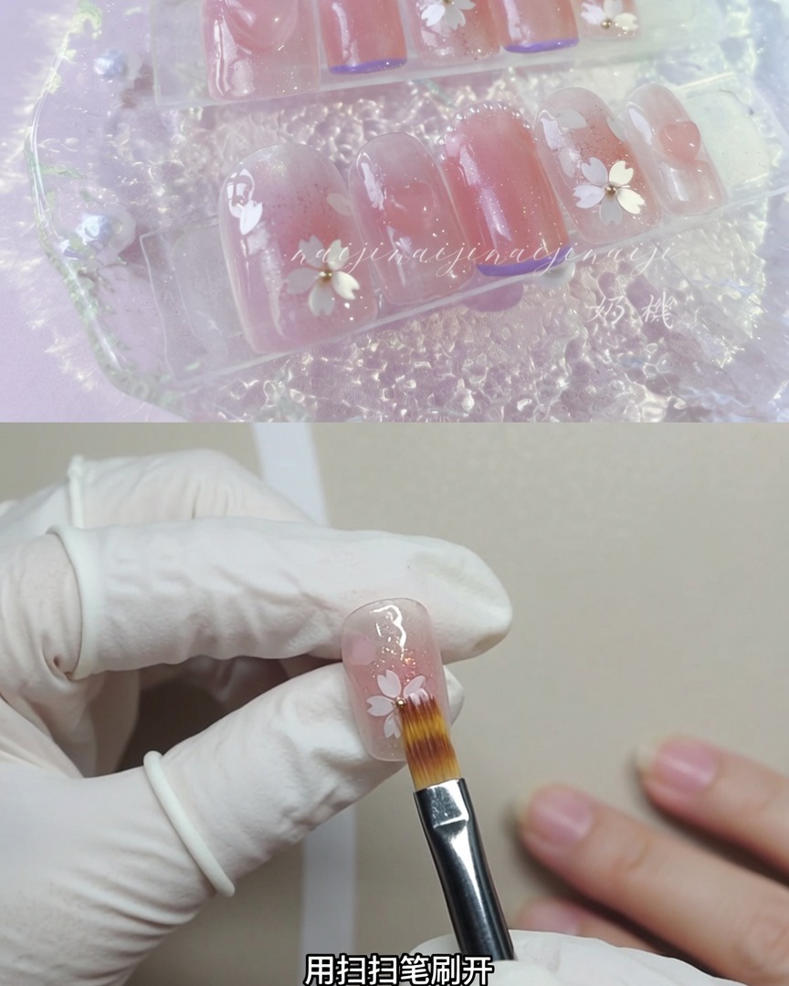 A gloved hand holding a soft dusting brush, lightly sweeping over a decorated fingernail to diffuse sparkly particles.