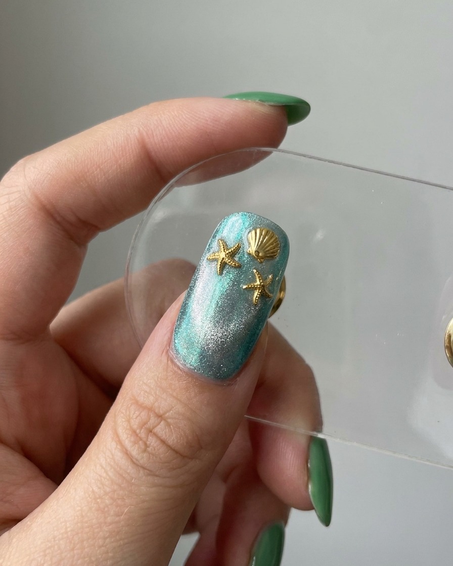 A finished nail preview showing a blue cat-eye base decorated with gold starfish and seashell charms.