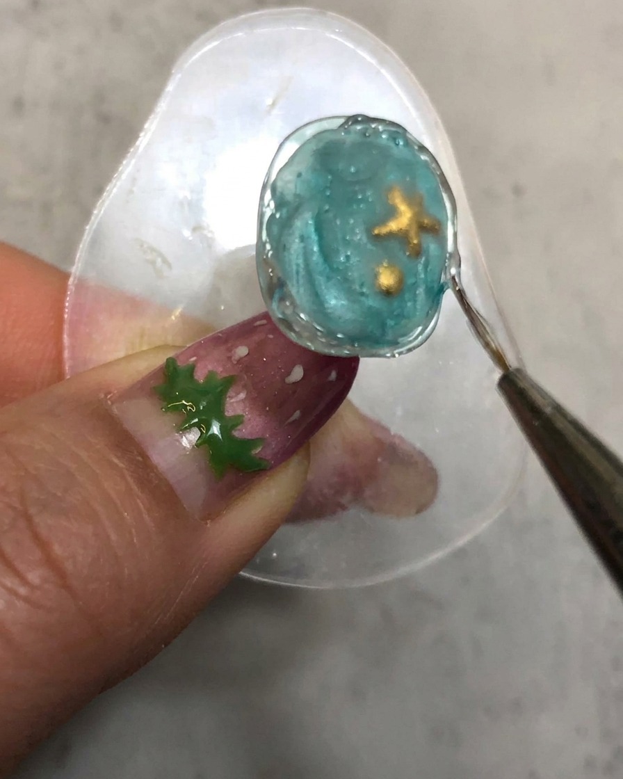 A detail brush tracing along the cured textured styling gel border of the nail.