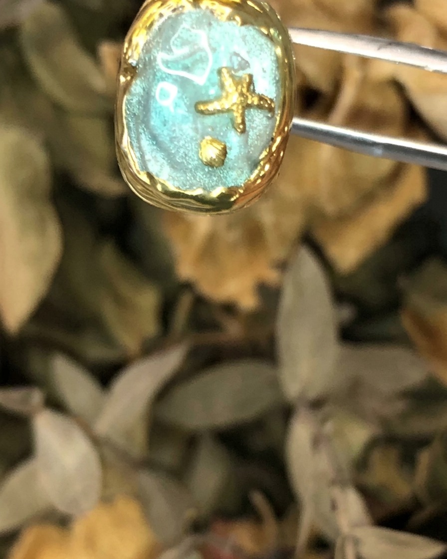 A close-up view of the finished Atlantis style nail art piece held by tweezers.