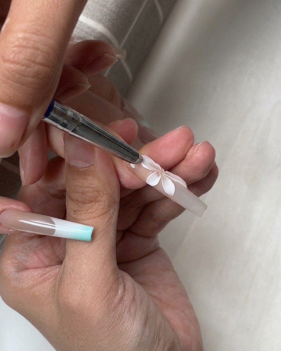 A silicone tool shaping multiple white 3D petals arranged into a complete flower on a nail.