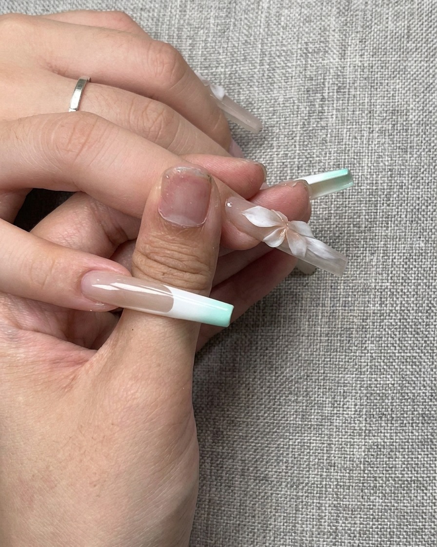 A small pink gradient effect created at the center of a white 3D sculpted flower on a nail.