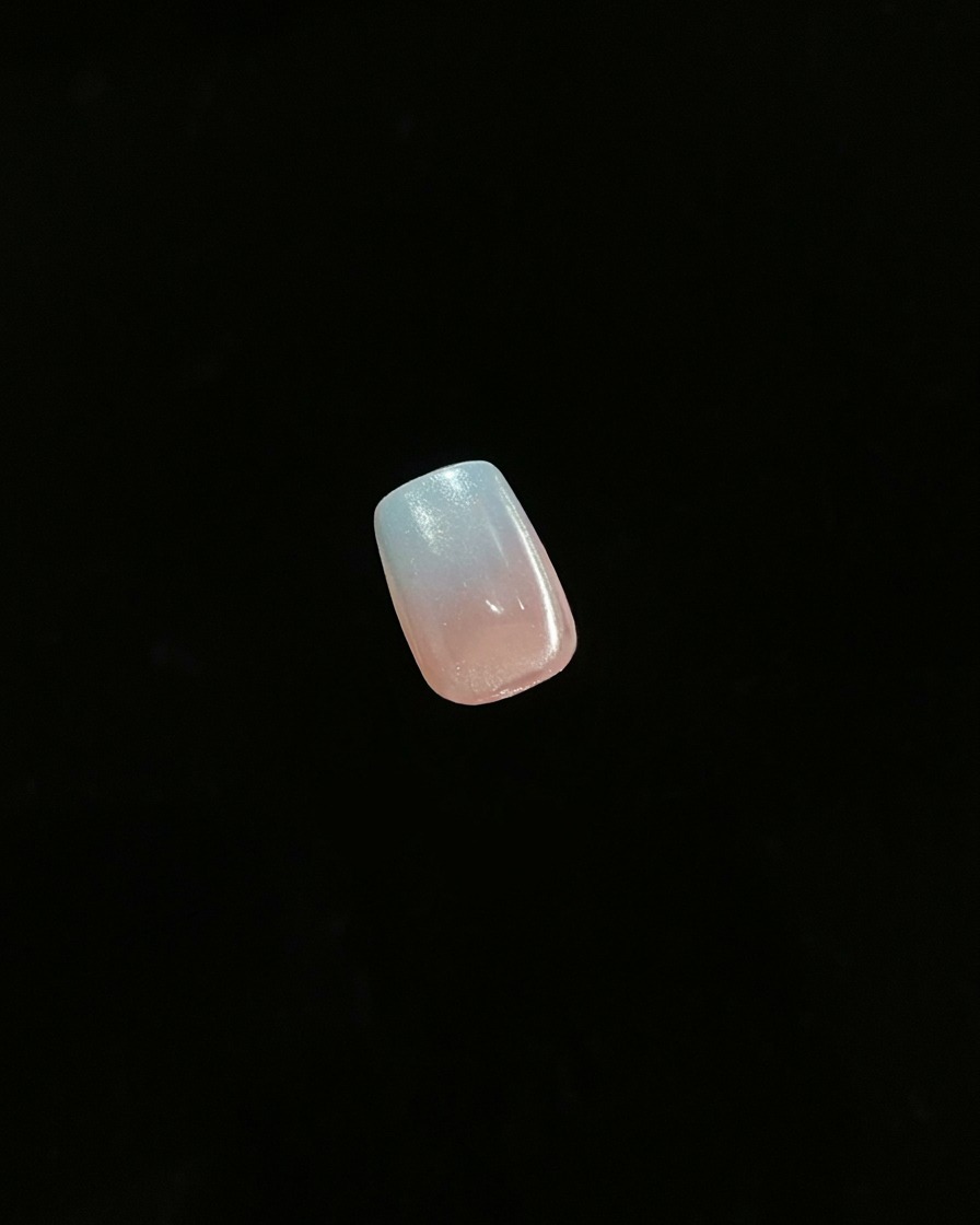 A close-up of a single finished nail showing a gradient ombre effect against a dark background.