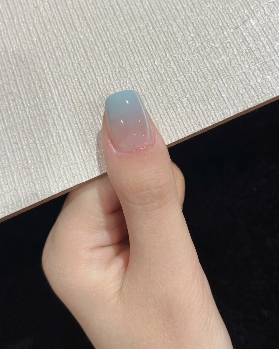 A thumb positioned under a portable UV LED lamp during the final top coat curing step.