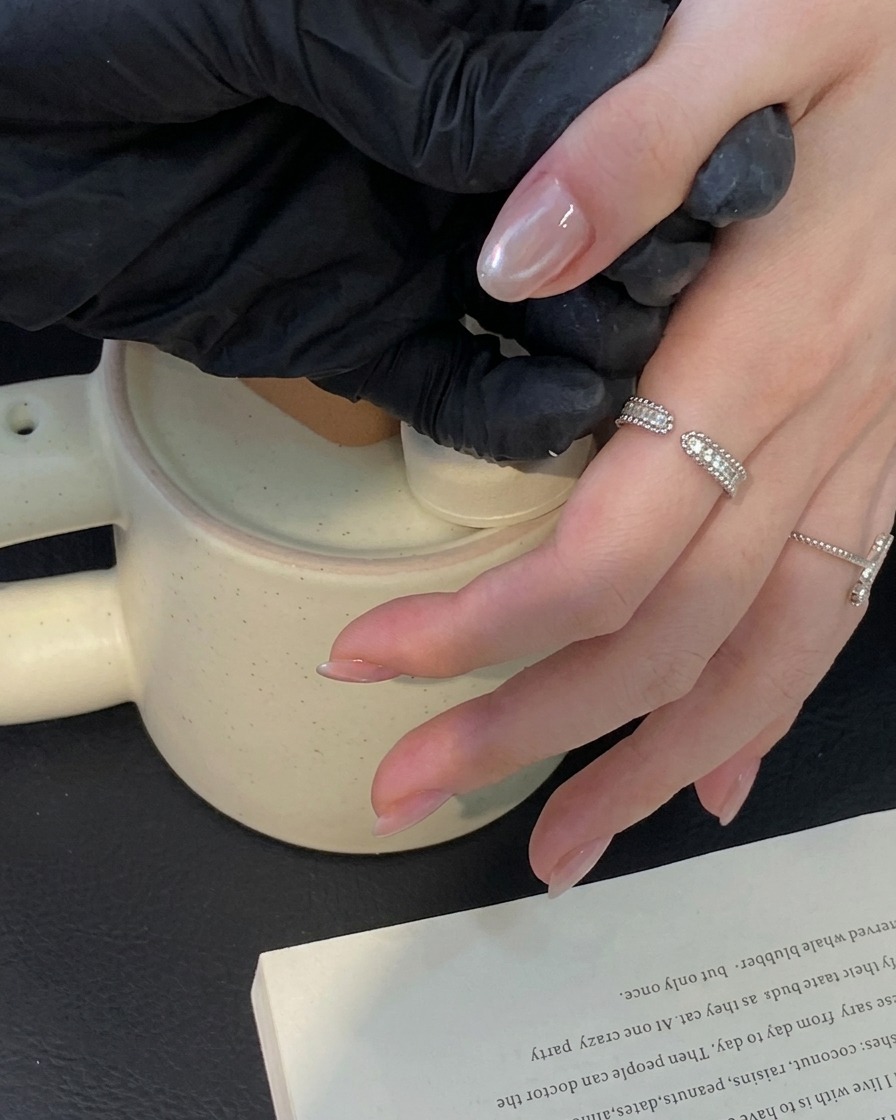 A brush applying a clear top coat layer over a finished cat eye manicure.