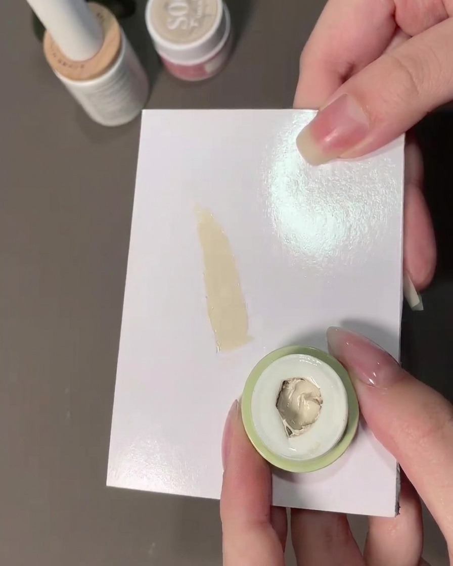 A sponge picking up milky white padding gel from a palette.