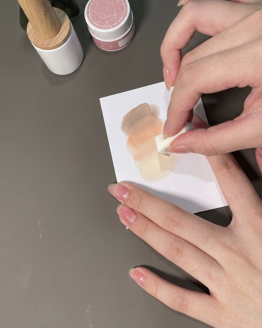 A sponge patting gel onto a nail to form an ombre gradient.