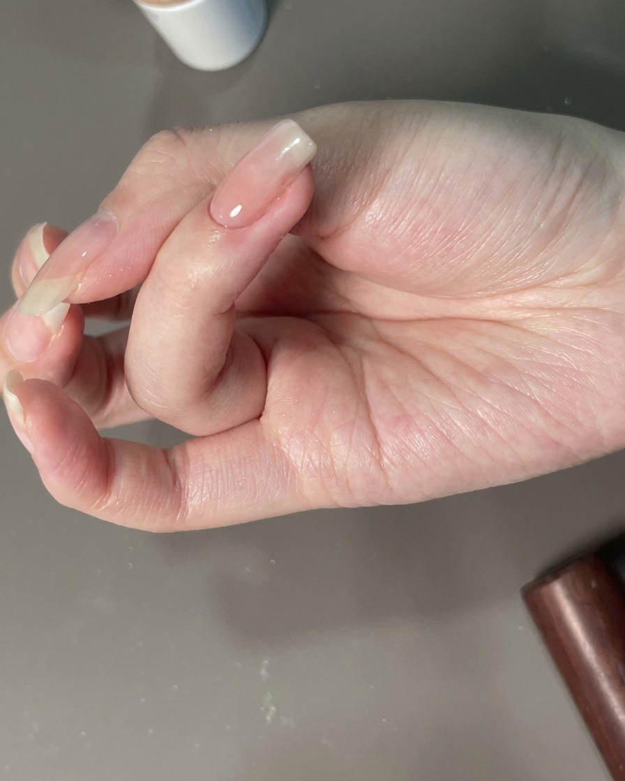 A hand positioned under a UV lamp for the final cure.