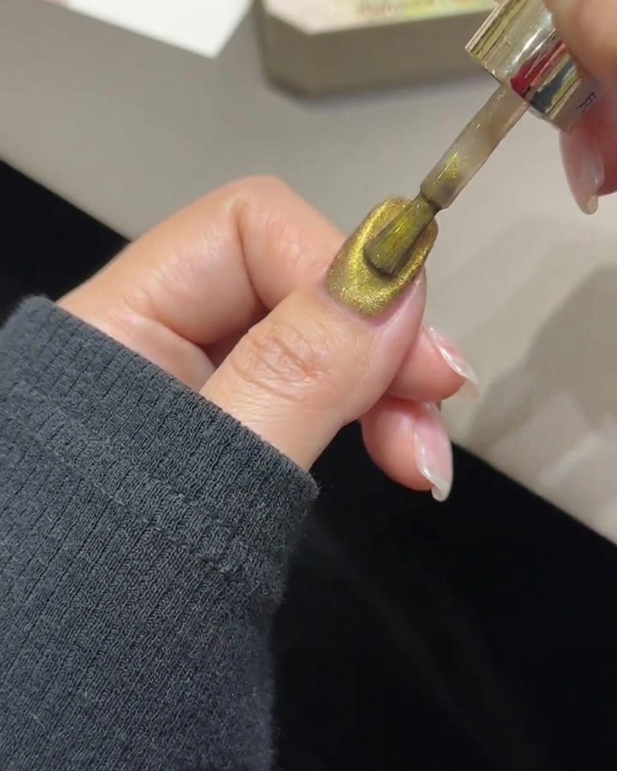 A magnetic wand tool hovering over a nail to concentrate gold magnetic particles into a light band.
