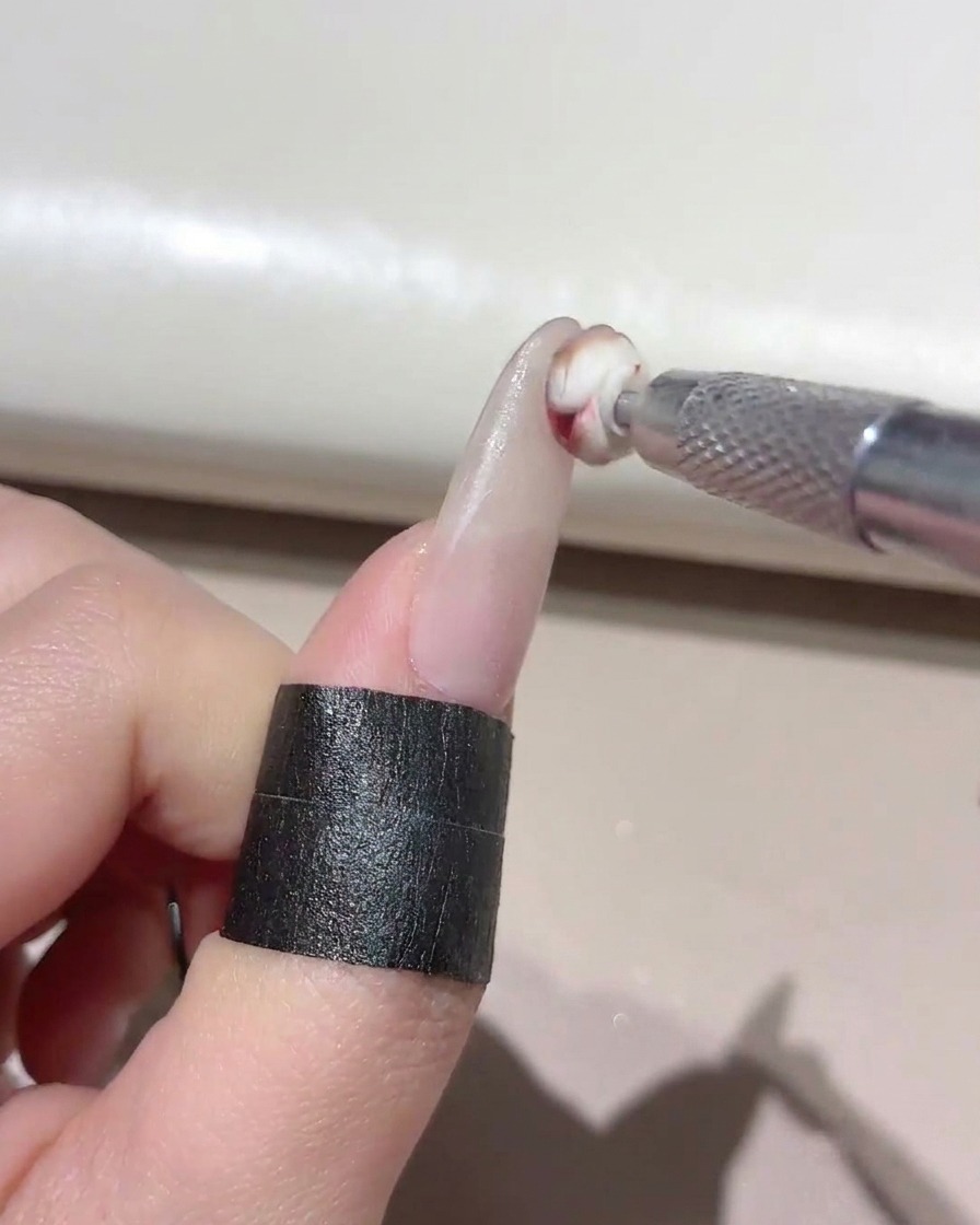 A small sponge tool dabbing mixed gel onto the tip of a manicured nail.
