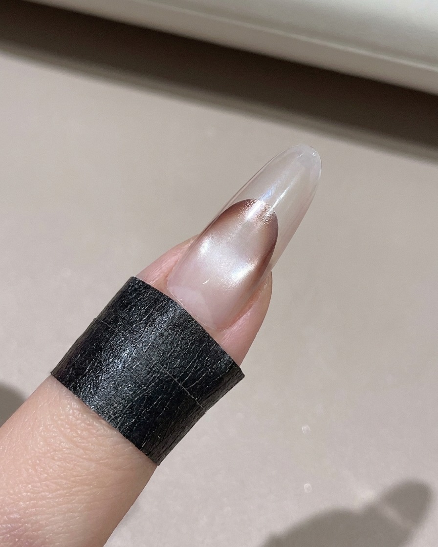 A lint-free wipe cleaning excess gel from the edge of a decorated nail.