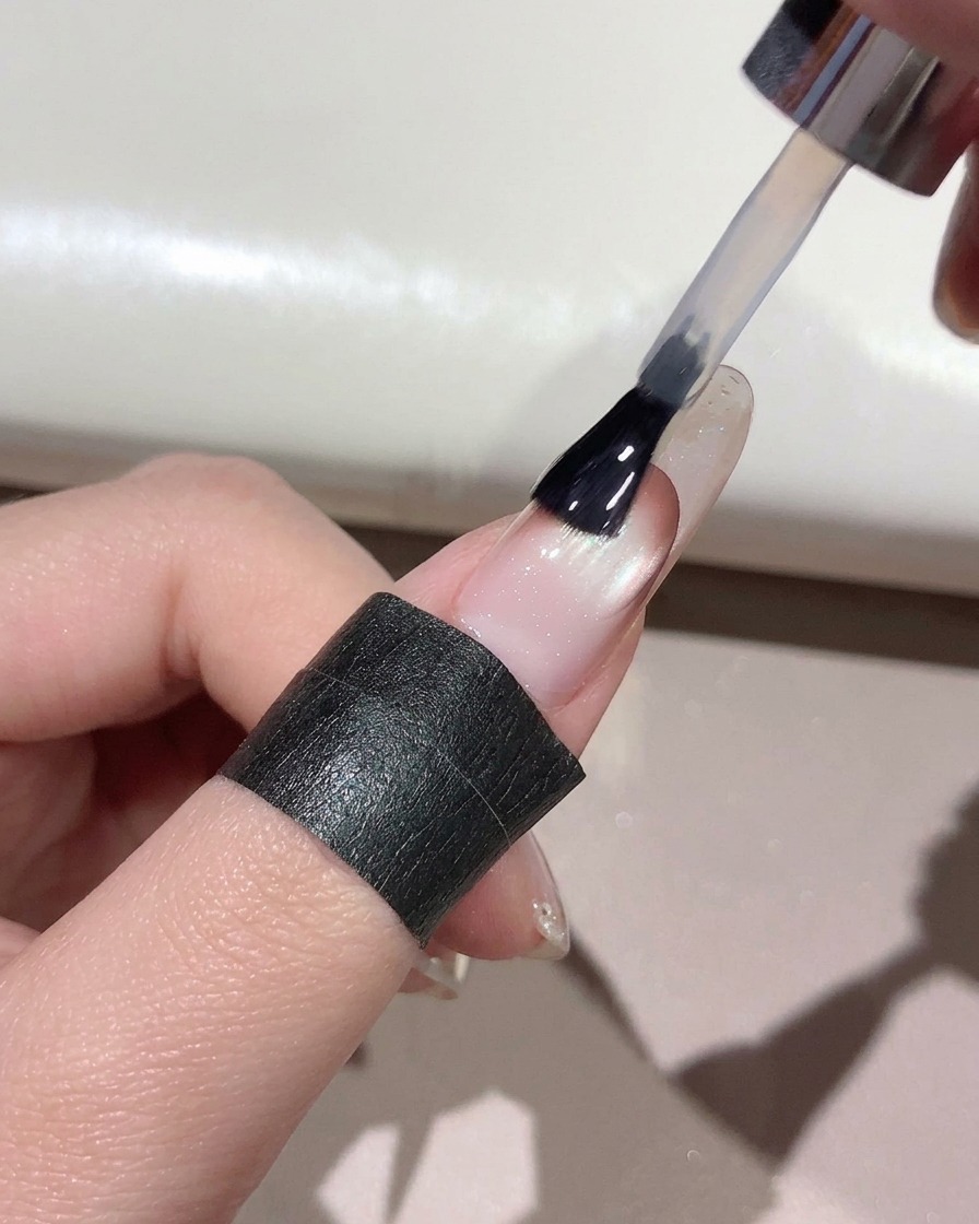 A brush applying clear top coat across the entire surface of a manicured nail.
