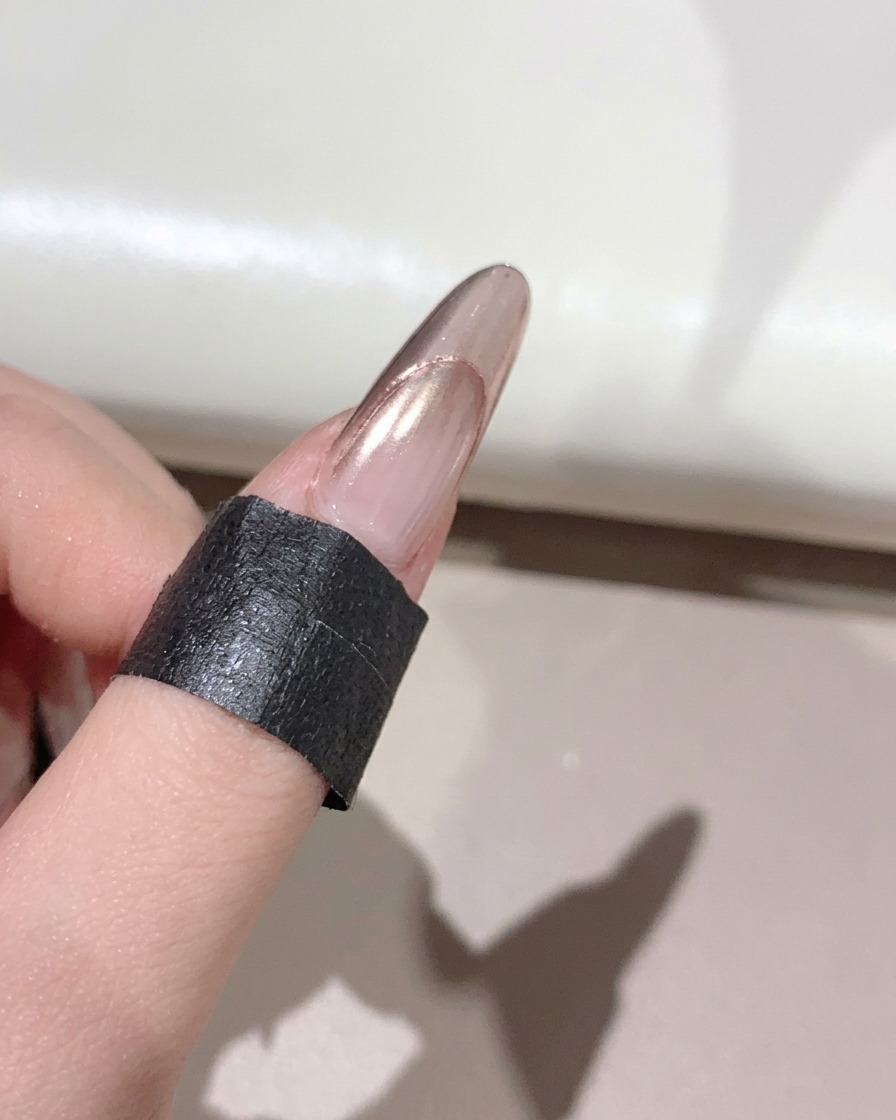 A fluffy brush sweeping away excess powder from a glossy manicured nail.
