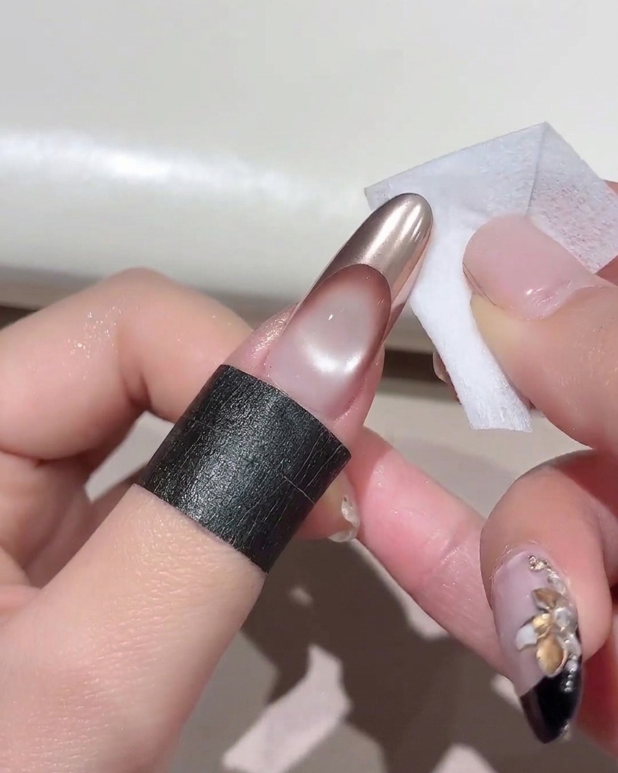 A small cleansing wipe cleaning the sides and base of a manicured finger.