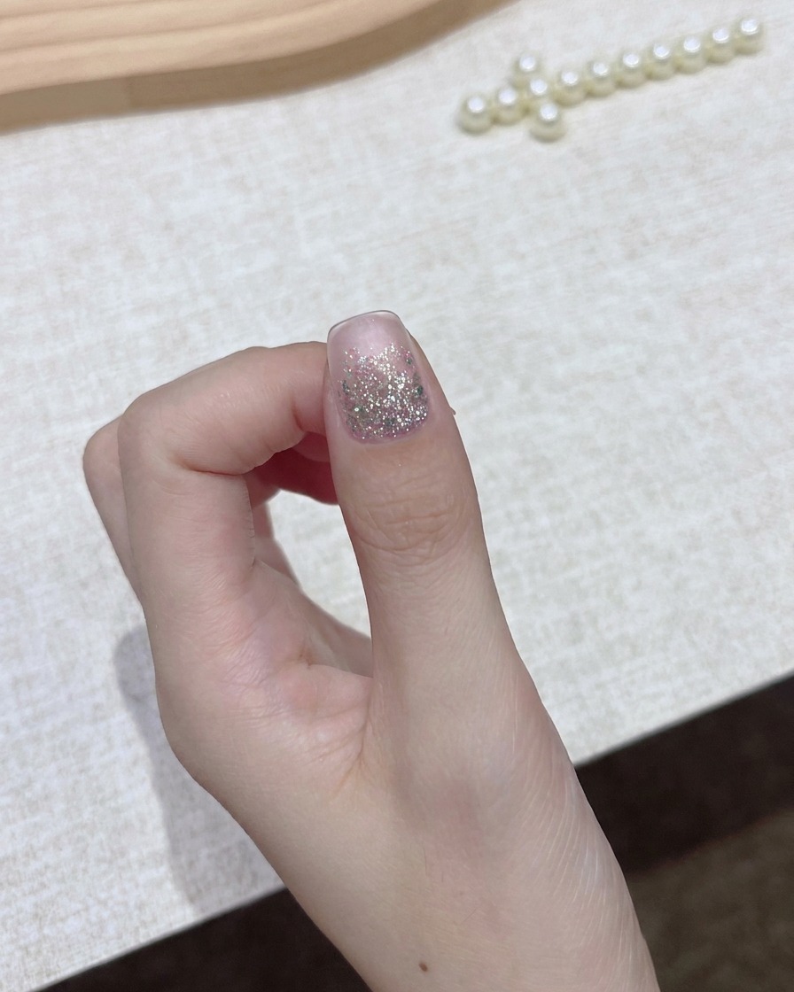 A hand holding a bottle of dark gel polish with the cap removed, preparing for the application step.