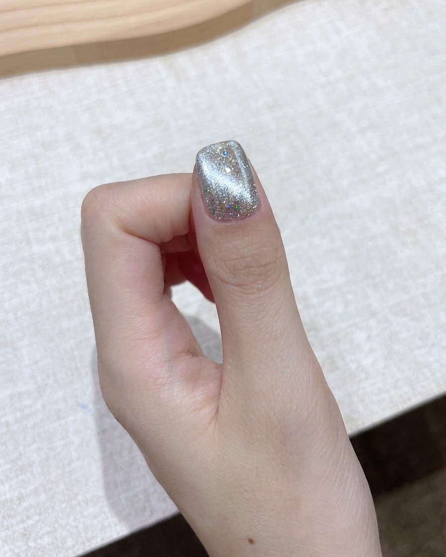 A rectangular block magnet held near a shimmering cat-eye gel nail to form a bright aurora beam.