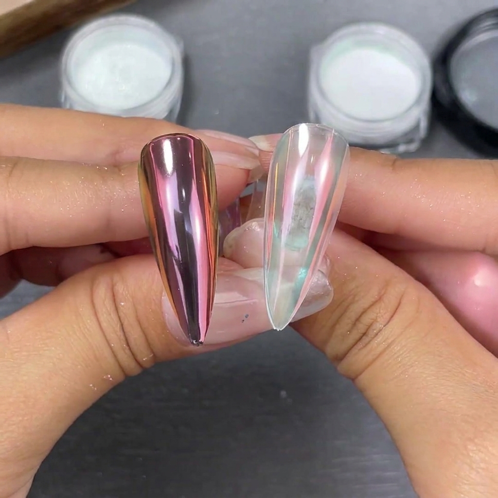 Two stiletto nail tips held side-by-side showing moonlight powder effects: a pinkish-purple shift on a black base and a soft pearlescent glow on a clear base.