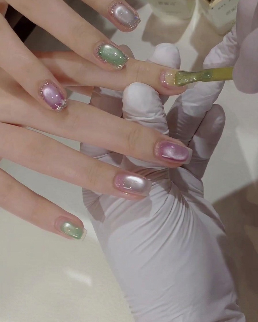 A detailed close-up of a nail brush applying bright yellow gel polish onto a natural fingernail.