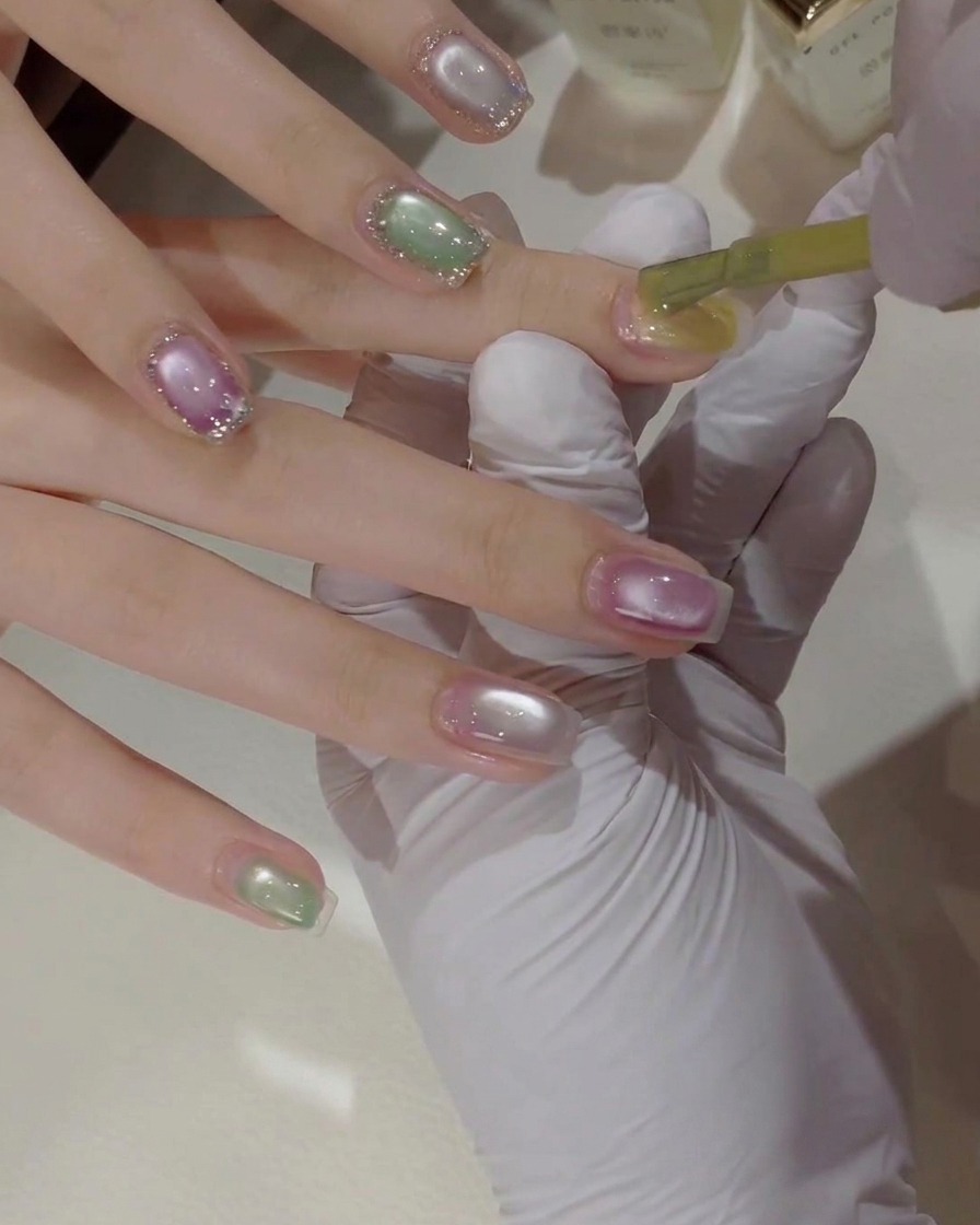 A brush applying cat eye gel to shape an ellipse on the nail.