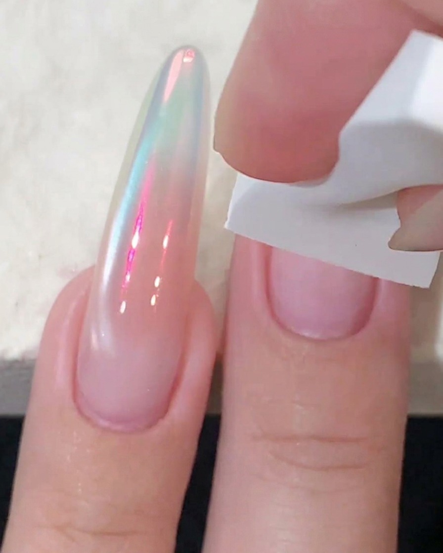 A white sponge patting pink blush gel onto the center of a fingernail to intensify the color.