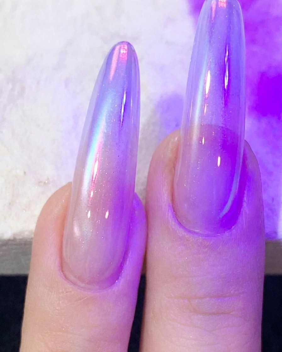 Fingers with cat-eye nail gel curing under a purple UV/LED nail lamp.