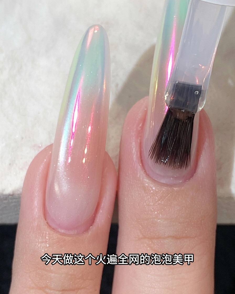 A brush applying top coat over a shimmering chrome-finished nail.