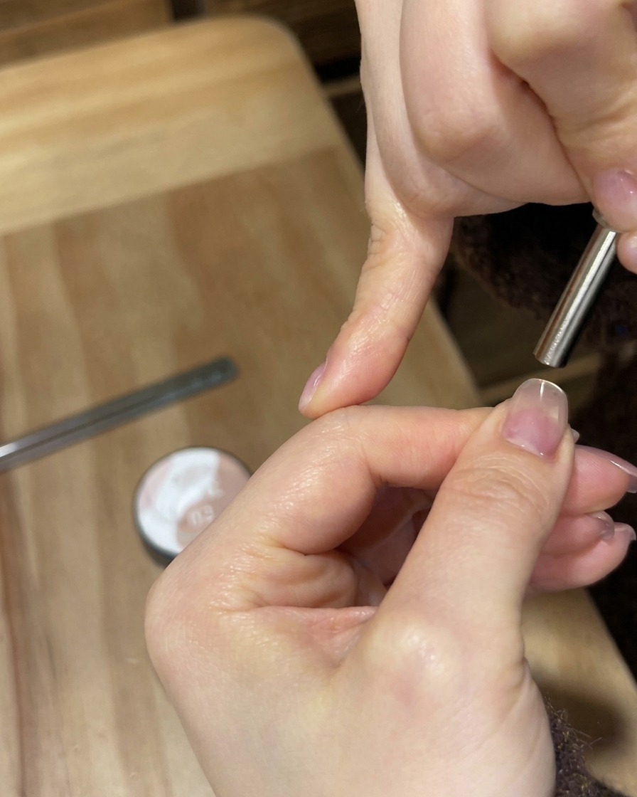 A portable white UV/LED lamp shining bright light over a fingernail to cure the gel coating.
