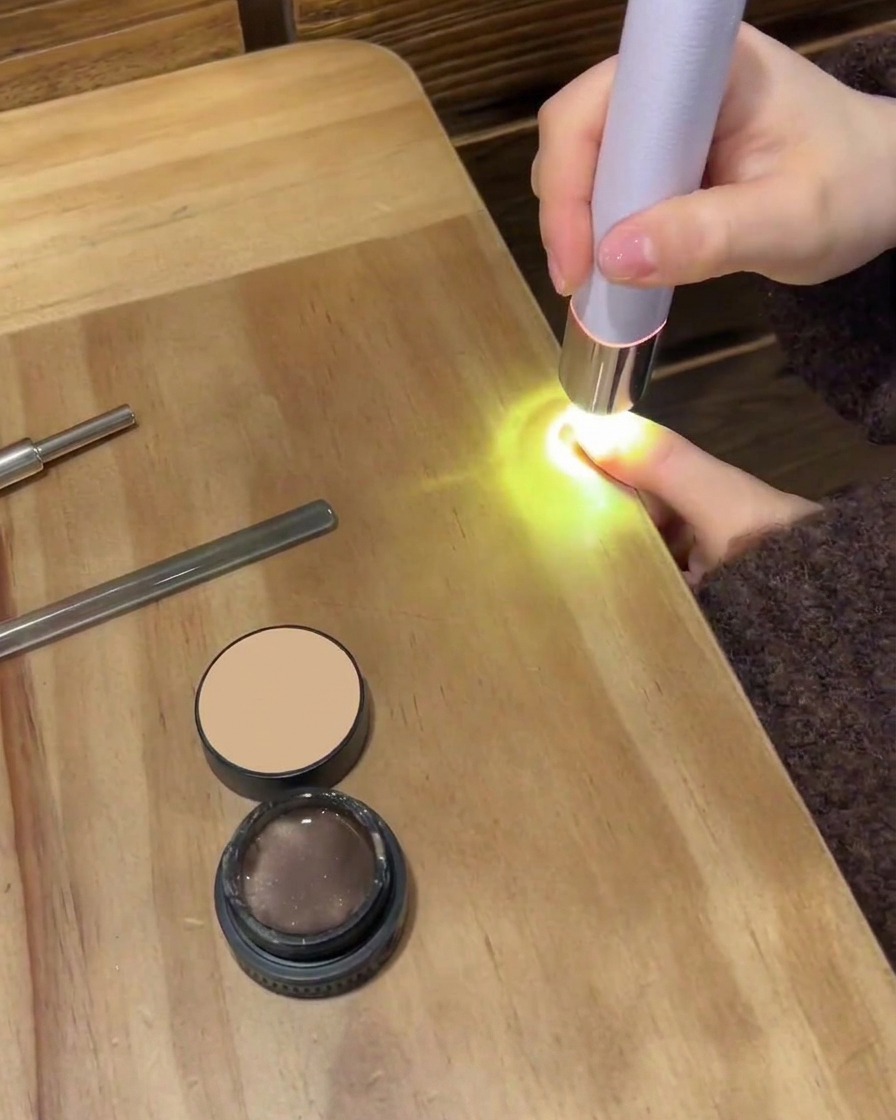 A small cotton pad wiping the surface of a nail to clear away the sticky residue.