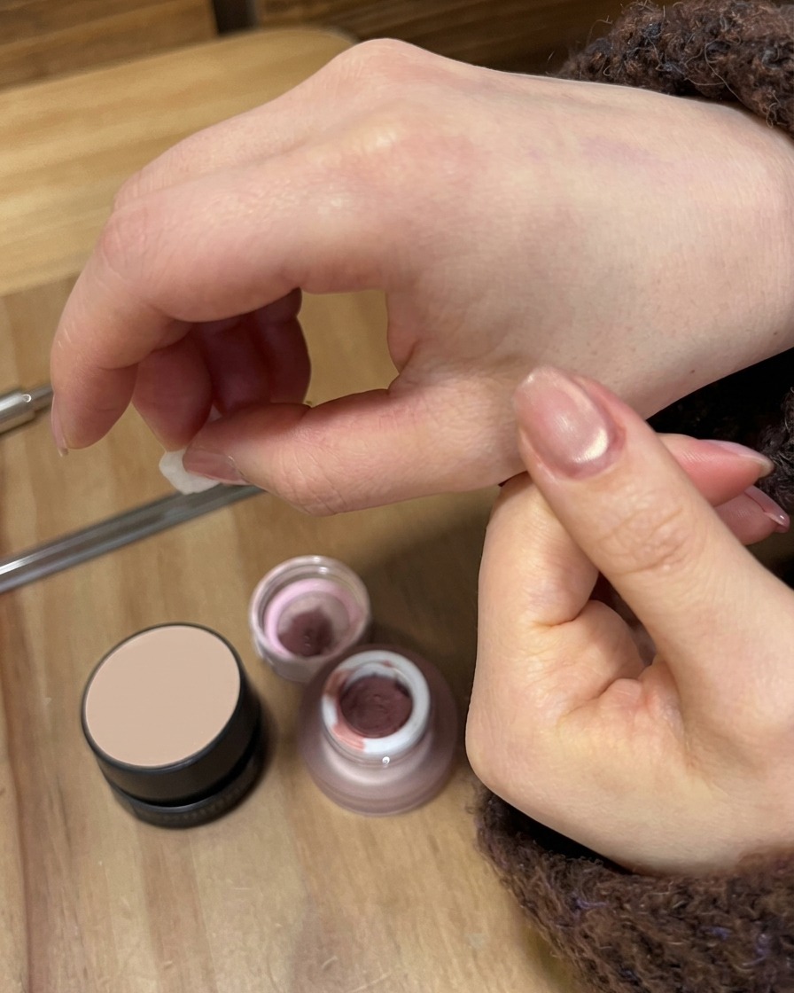 A mini UV/LED flashlight curing a pink gradient design on a fingernail.