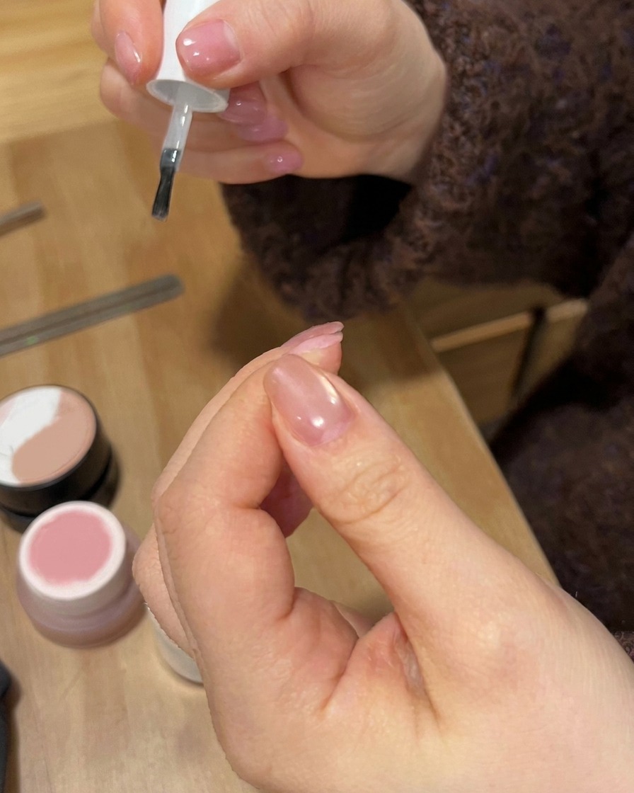 A nail polish brush applying a glossy clear coat over a finished gradient nail design.